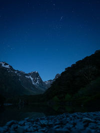 Scenic view of snowcapped mountains against starry sky at night