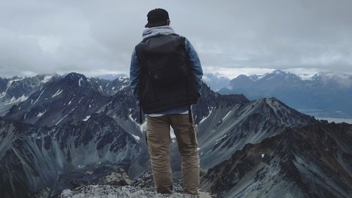 Rear view of man standing on snowcapped mountain