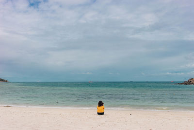 Rear view of person standing on beach against sky