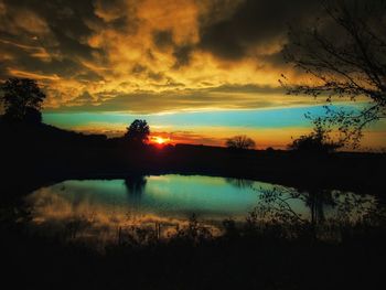 Silhouette trees by lake against sky during sunset