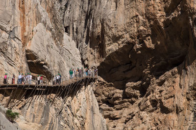 People walking on footbridge by mountain