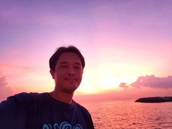 Portrait of mature man smiling against sea during sunset