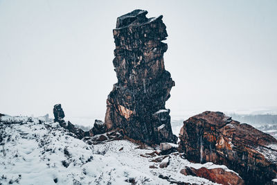 Rock formation on snow covered land against sky