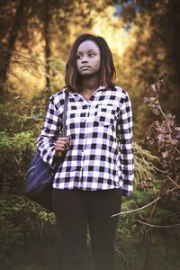 Portrait of young woman standing in forest