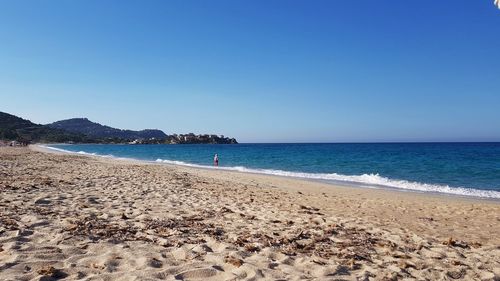 Scenic view of beach against clear blue sky