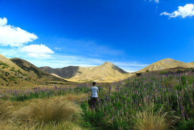 Rear view of man standing on field against sky