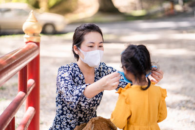 Young mother put healthy face mask on her daughter's face.