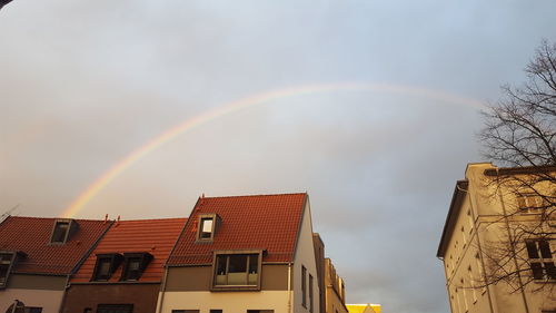 Low angle view of rainbow over buildings against sky