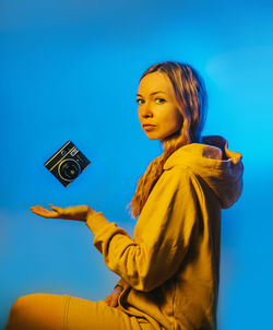 Low angle view of young woman using digital tablet against blue background