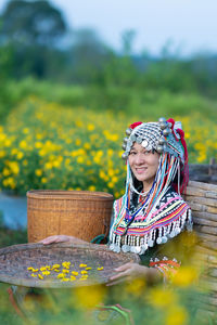 Portrait of woman in traditional clothing holding straw basket sitting at farm