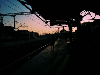 Silhouette railroad tracks against sky at night