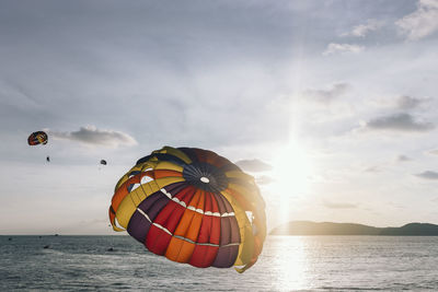 Parachutes at sea against sky