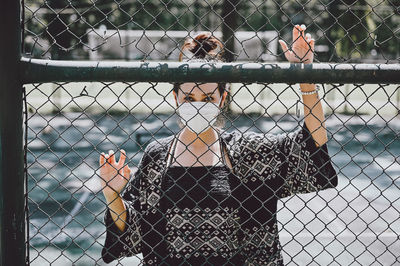 Young women wear surgical protection mask behind the cage