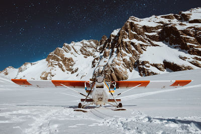 Propeller airplane on snow covered field at dusk