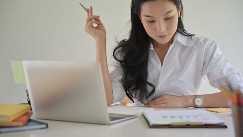 Midsection of woman using mobile phone while sitting on table