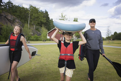 Mother and children carrying paddle board