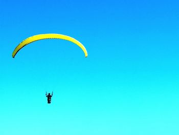 Low angle view of paragliding against clear blue sky