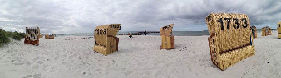 Panoramic view of hooded beach chairs against sky