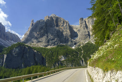 Country road by mountains against sky