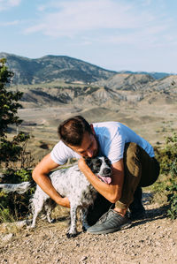 Male owner of spaniel dog walking against mountains background.