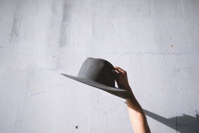 Low section of person holding umbrella standing against wall