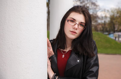 Portrait of beautiful young woman standing against wall