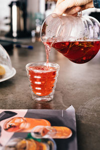 Close-up of hand pouring drink in glass on table