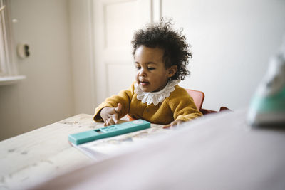 Girl sitting at table and playing