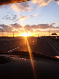 Vehicles on highway against sunset sky seen from car windshield