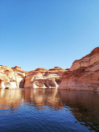 Rock formations in water against clear blue sky
