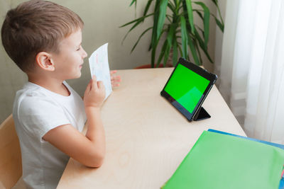 Rear view of boy looking at table