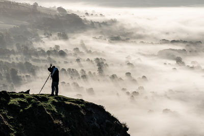 Man standing on rock against sky