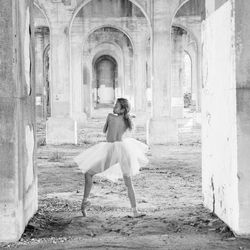Shirtless ballet dancer wearing tutu standing in abandoned building