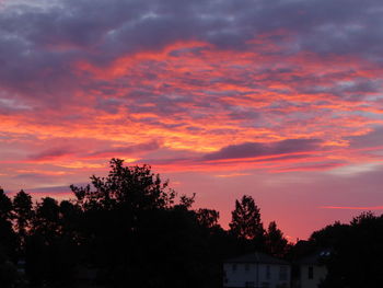 Silhouette trees and buildings against sky during sunset