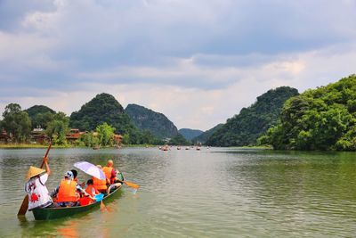 People in boat on river against sky