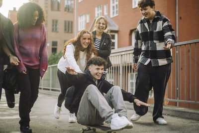 Cheerful male and female friends having fun while playing on footpath