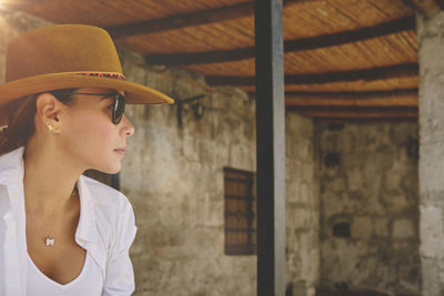 Portrait of young woman wearing hat standing in abandoned building