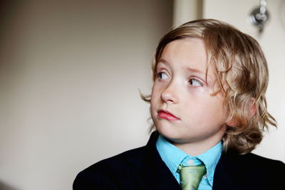 Close-up of boy wearing suit looking away and standing at home