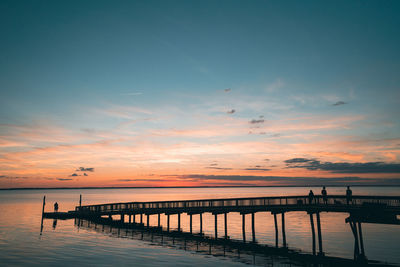 Pier over sea against sky during sunset