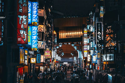 People on illuminated street in city at night