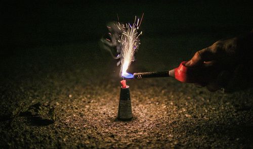 Cropped hand holding sparkler at night