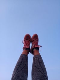 Low section of person standing against blue sky