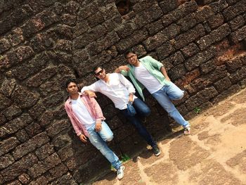 Portrait of male friends standing against wall at historic building