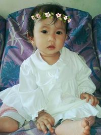 Portrait of cute baby girl relaxing on bed at home