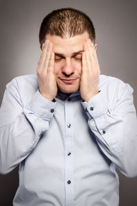 Portrait of young man standing against gray background