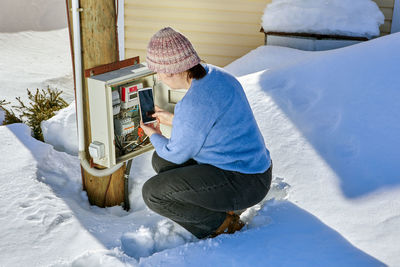 Rear view of woman sitting on snow covered field