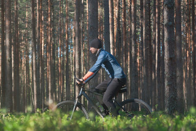 Side view of man riding bicycle in forest