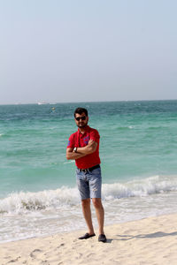 Full length portrait of young man standing on beach