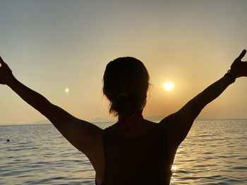 Rear view of silhouette woman against sea at sunset