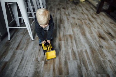 Boy playing with bulldozer toy on hardwood floor at home